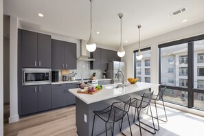 Fully equipped kitchen stocked with basic cooking essentials. Includes stainless steel appliances and kitchen island seating.