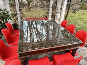 10 seats around antique, hand-carved Persian teak table under pergola. 