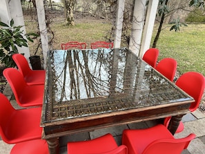 10 seats around antique, hand-carved Persian teak table under pergola.