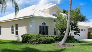 Tropical landscaping with several palm trees surrounds the property