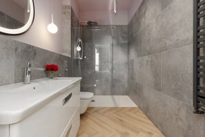 A modern bathroom with sleek gray tiles, a bathtub, and wooden flooring, giving a luxurious and elegant feel to the space.