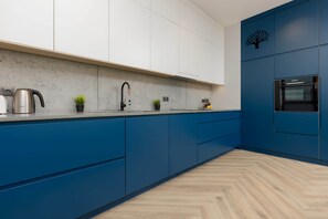 A stylish kitchen with white upper cabinets and vibrant blue lower cabinets, featuring a clean, modern layout with ample countertop space.