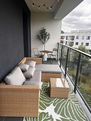 Spacious balcony with outdoor furniture. 