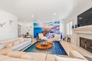 A large luxurious family room, nicknamed "Greek Escape - The Mykonos room" with a full wall mural of the Greek Isle Mykonos.