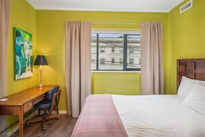 A tranquil green-toned room with a desk and queen-sized bed, perfect for relaxation and focus.