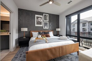 Primary Bedroom with King bed, smart TV, floor to ceiling windows, and en-suite bathroom.
