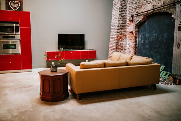 The open concept living area features a unique floor to ceiling brick wall that is from the original construction of the warehouses. 