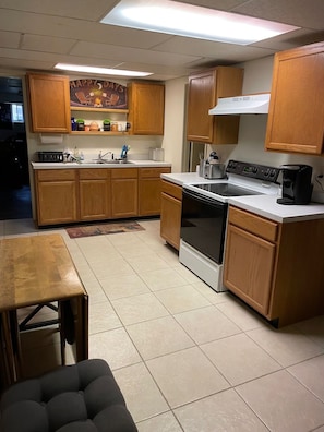Kitchen with range, sink, microwave, Keurig, ice maker, pots, and baking sheets.