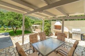 Outdoor living with traditional and propane BBQs, swinging couch, & orange tree