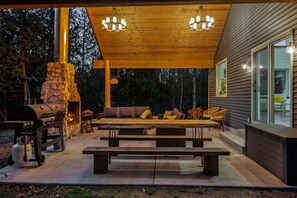 Relish the expansive outdoor living space, featuring a magnificent outdoor fireplace. Share laughter and stories under the starry night sky, enveloped by the tranquil forest setting.