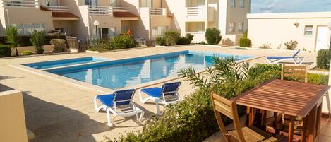 Piscina comunitária e terraço privado com mesa e cadeiras