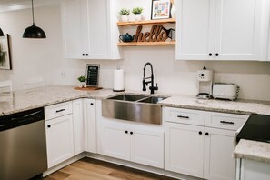 The newly renovated kitchen features a stainless steel apron front sink and stainless steel appliances.