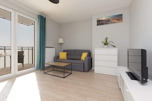 Another angle of the bedroom, highlighting a seating area with a small table and plenty of natural light from large windows.