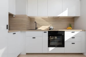 A modern kitchen with white cabinets, a wooden countertop, and a built-in oven, combining practicality with style.