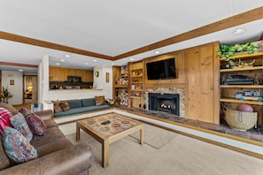 Spacious living area with open floor plan, wood-burning fireplace, and flatscreen TV.