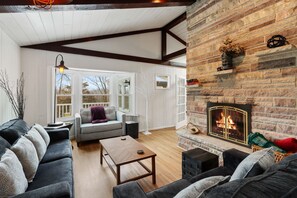 Spacious living room with vaulted ceilings and fireplace (during winter season).