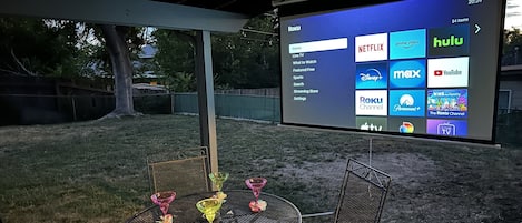 Your private backyard escape with cozy seating, a dining table, and a projector for ultimate relaxation!