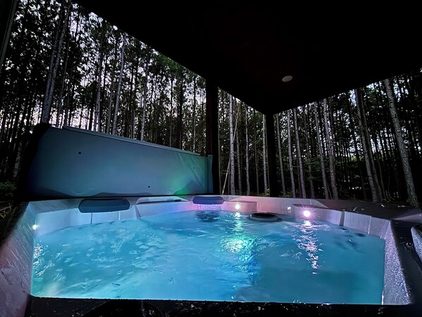 Unwind in a forest hot tub with warm bubbles & cozy covered patio vibes.