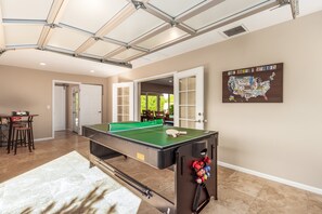 Game Room with board games, TV, multi-purpose game table for ping pong, air hockey, and pool, and access to the backyard.