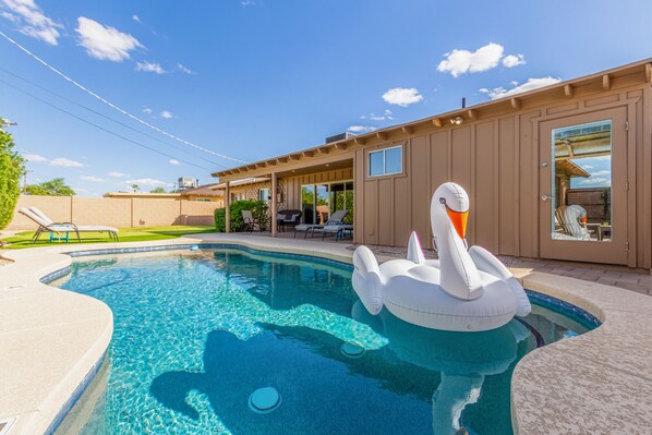 Backyard accessible from the kitchen with ample outdoor seating, pool, and putting green.