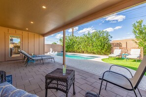 Backyard accessible from the kitchen with ample outdoor seating, pool, and putting green.