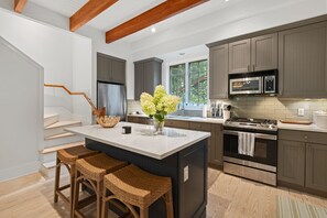 The well-equipped kitchen includes a center prep island with bar stools for entertaining,