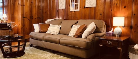 Comfy 3-seat sofa with warm, honey pine wood panel walls.