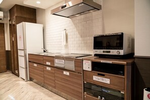 The kitchen space is fully equipped with a refrigerator, microwave, tableware for children, and a pot for milk.