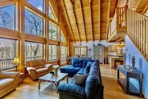 Open concept Living room with bamboo flooring, wooden ceiling, comfortable couches and arm chairs