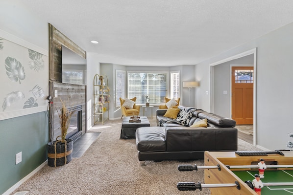 comfortable leather couch, accent chairs, decorative fireplace and 65" smart TV