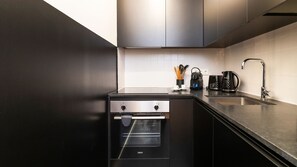 A compact yet functional kitchenette equipped with essential appliances like a fridge, oven, and coffee maker. It's ideal for preparing light meals and snacks during your stay. #practical #modern