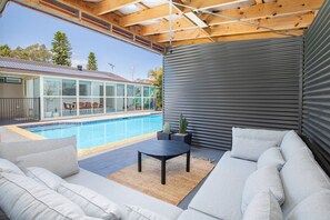 The outdoor cabana features a large corner sofa overlooking the pool 
