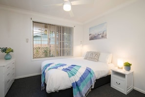 The light and airy bedroom offers a queen-size bed with side tables and reading lamps.
