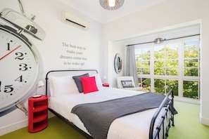 The primary bedroom boasts a leafy outlook from large windows best enjoyed from the queen-size bed.