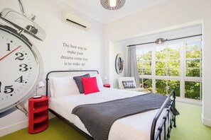 The primary bedroom boasts a leafy outlook from large windows best enjoyed from the queen-size bed.