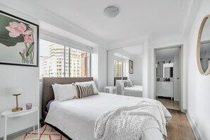 On the first floor, the second bedroom boasts sweeping windows above the queen bed with skyline and harbour glimpses. Make use of the large mirrored wardrobe and attached ensuite bathroom. 
