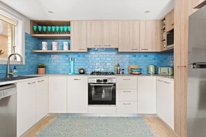 The kitchen has generous bench space for meal preparation and a funky blue tiled splashback creating a fun pop of vibrant colour. 
