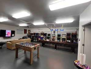 Game room with 75" TV, Shuffle Board Table, Foosball, Dart Board and Arcades.