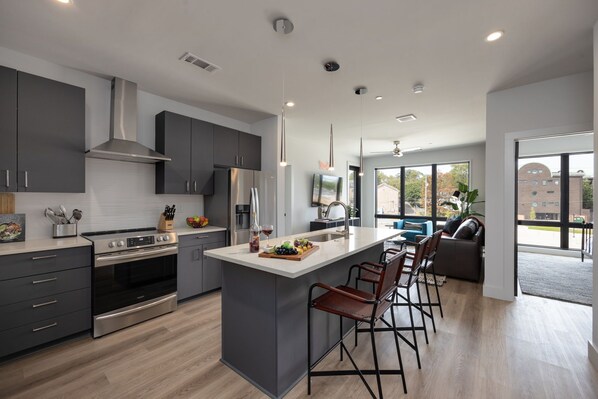 Fully equipped modern kitchen boasting brand-new stainless-steel appliances and stocked with all culinary essentials for ease and convenience. Kitchen island offers ample counter space and bar seating.