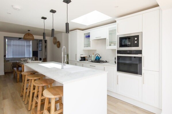 The fully-equipped kitchen, with sleek white cabinets and marble worktops, has everything you need to cook and prepare meals.