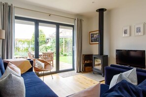 Lounge with huge corner sofa, TV and wood burner.