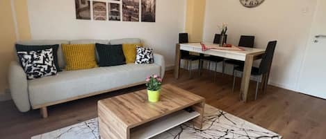 Wohnzimmer mit Schlafcouch und großem Esstisch