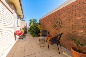 The outdoor patio features seating, a gas BBQ, and dining table (located on the other side). The laundry is located at the back.