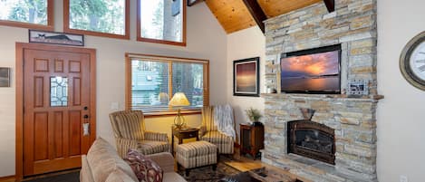 Enjoy a cozy retreat in this living room with a large TV for streaming, a gas fireplace to set the mood, ample seating, and two armchairs ideal for reading and relaxing