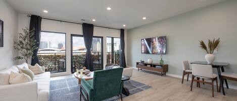 Bright open floor living space featuring smart flat-screen TV,
designer furnishings connected to the kitchen and dining area.