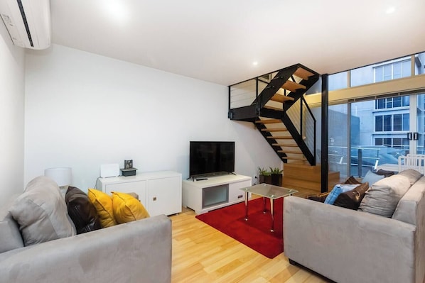 A grand staircase up to the lofted bedrooms defines the living area.