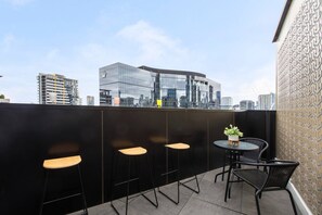 The private balcony is furnished with alfresco seating to enjoy the city night lights with a drink. 