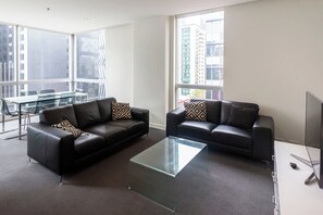 The living room offers two leather sofas situated in front of a TV.