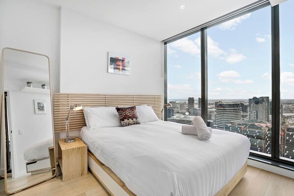 Sprawling views continue in the bedroom with a plush queen bed and standing mirror.