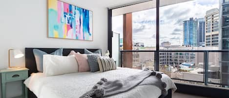 Rest easy in the plush king bed, offering chic artwork and sprawling views across the CBD.